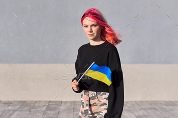 Female pupil teen with Ukraine flag, grey outside wall background