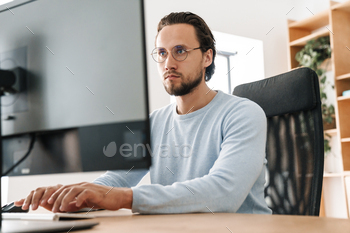 Image of targeted unshaven programmer man functioning with laptop